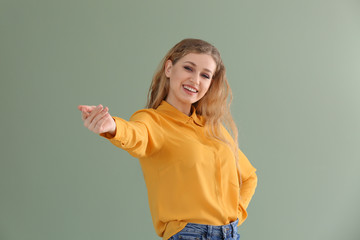 Beautiful young woman inviting viewer against color background