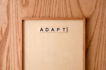 ADAPT word block on wood background. 