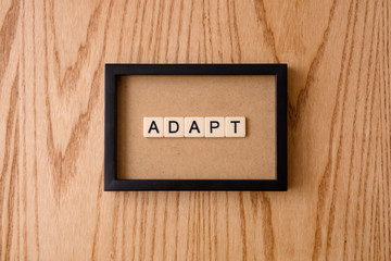 ADAPT word block on wood background. 