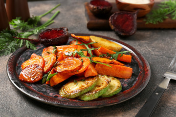 Plate with tasty cooked vegetables on dark table