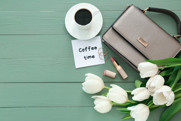 Composition with beautiful tulips, female accessories and cup of coffee on color wooden background