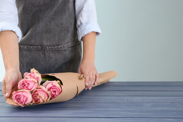 Florist holding beautiful bouquet at table