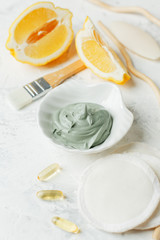 Preparing cosmetic volcanic clay mask with citrus lemon and cosmetic oil on light gray background, concept of natural organic cosmetic products for face body health care