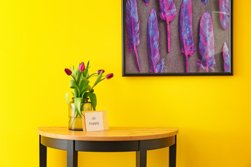 Vase with beautiful tulips on table near color wall
