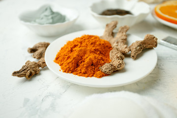 close up of body care cosmetic products with turmeric curcuma powder on light gray background, concept of natural organic homemade cosmetic for face body health skin care