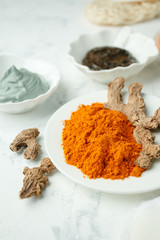 close up of body care cosmetic products with turmeric curcuma powder on light gray background, concept of natural organic homemade cosmetic for face body health skin care