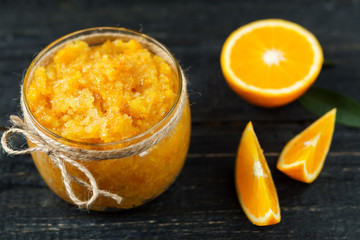 Homemade orange jam on a wooden table with pieces of fruit