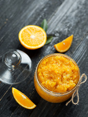 Homemade orange jam on a wooden table with pieces of fruit