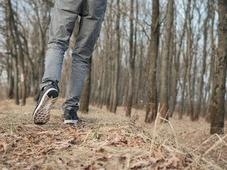 Close-up of feet in sneakers in a dry early spring forest
