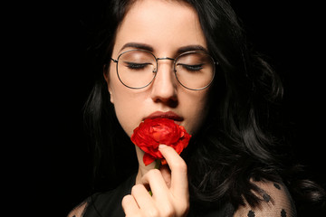 Portrait of beautiful woman with flower on dark background