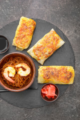 Slate plate with tasty fried spring rolls on table