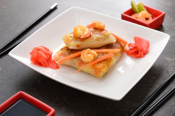 Plate with tasty fried spring rolls on table