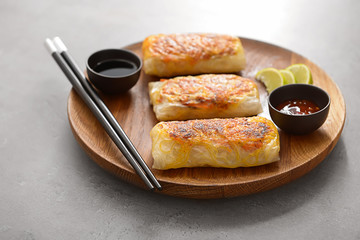 Plate with tasty fried spring rolls on table