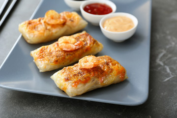 Plate with tasty fried spring rolls on table