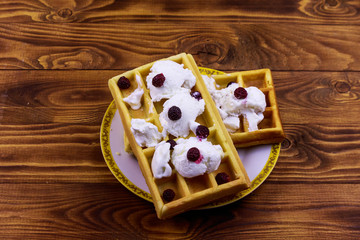 Belgian waffles with ice cream and blackberries on wooden table