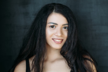 Fototapeta premium Closeup portrait of peaceful girl with beautiful long black hair. Emotional lady with cute smile. Happy facial expression.