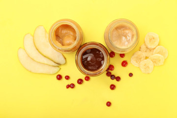 Jars with different healthy baby food on color background