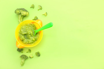 Bowl with healthy baby food on color background