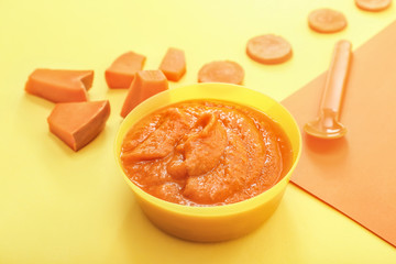 Bowl with healthy baby food on color background