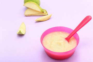 Bowl with healthy baby food on color background
