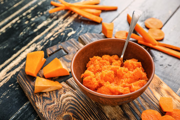Bowl with healthy baby food on dark wooden background