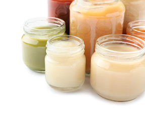 Jars with different healthy baby food on white background