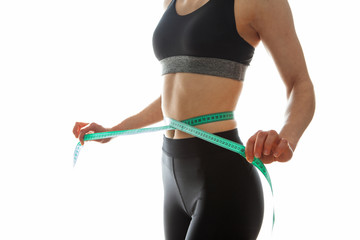 Slim young woman measuring her thin waist