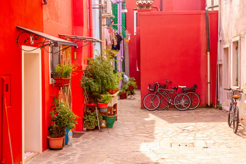 Fototapeta na wymiar Beautiful red houses with bicycles. Colorful houses in Burano island near Venice, Italy.