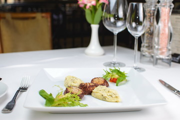 grilled scallops with celery puree and vegetables. on a white plate