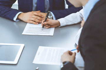 Group of business people and lawyer discussing contract papers sitting at the table, closeup. Businessman is signing document after agreement done