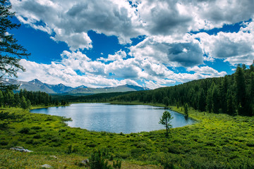 Fototapeta na wymiar Mountain landscape, white clouds, lake and mountain range in the distance. Fantastic sunny day in mountains, large panorama. Location is in Altai, Russia.