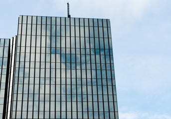 Fototapeta na wymiar modern skyscraper building with reflecting windows under a blue sky with light white clouds