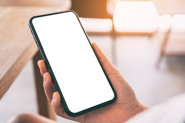 Mockup image of woman's hands holding black mobile phone with blank white screen in cafe