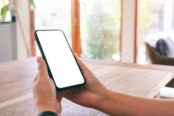 Mockup image of woman's hands holding black mobile phone with blank white screen in cafe
