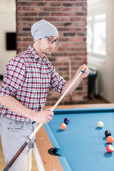 Fashionable snooker player wipes a cue with chalk ready to start the game.