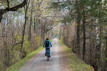 sporty woman riding a bicycle along a dirt path through a beautiful spring time colorful forest