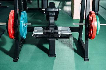 athletic barbell in an empty gym. sports equipment red and blue weighting.