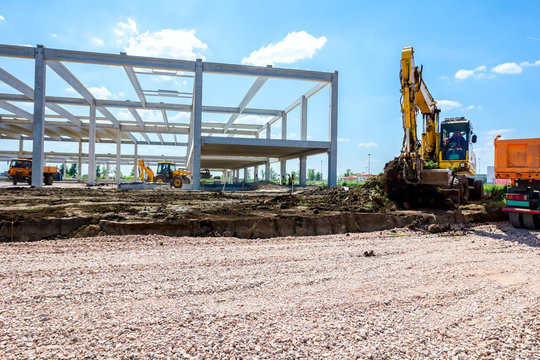 Backhoe is loading a truck with ground on building site