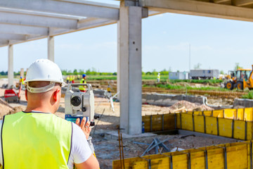 Civil engineer, geodesist is working with total station on a building site