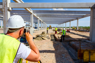 Civil engineer, geodesist is working with total station on a building site