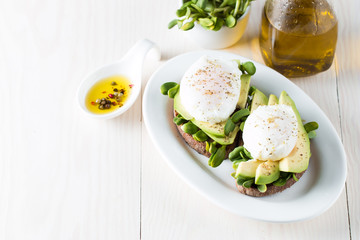Avocado toast, cherry tomato on wooden background. Breakfast with toast avocado, vegetarian food, healthy diet concept. Healthy sandwich with avocado and poached eggs.