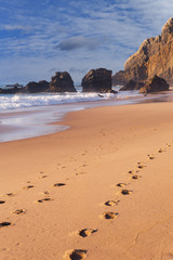 Atlantic Ocean waves splashing on a hot sandy beach near the Portuguese city of Sintra