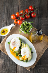 Avocado toast, cherry tomato on wooden background. Breakfast with toast avocado, vegetarian food, healthy diet concept. Healthy sandwich with avocado and poached eggs.