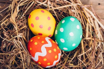 Fototapeta na wymiar Beautiful Easter multi color egg in straw on wooden