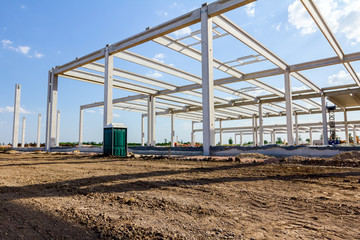 Concrete edifice under construction with mobile plastic toilet