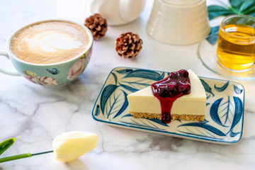 Homemade Blueberry cheesecake on white dish and coffee latte art.