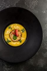 Homemade pumpkin cream soup on dark plate