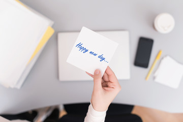 Woman clerk sitting holding note paper sticker with Happy new day phrase. Business concept. Concept.