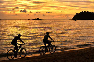Fototapeta na wymiar Two cyclist relaxing and enjoyed beautiful sunset along the beach in pangkor island, perak malaysia