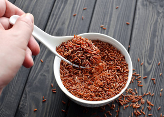 hand holdind a spoon with red rice pouring